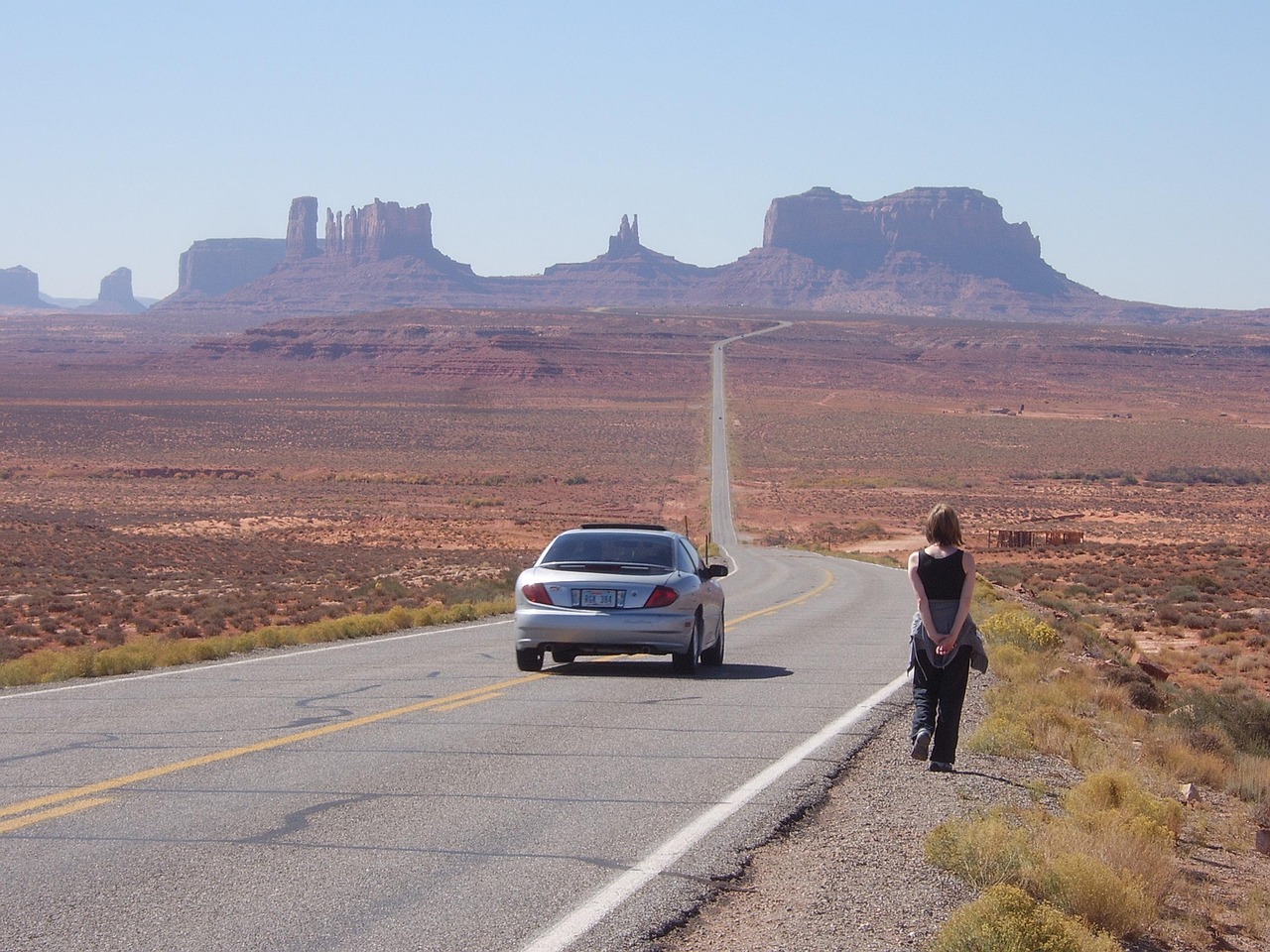 Car on a straight desert highway under a clear sky